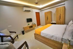 a bedroom with a bed and a chair and a tv at Hotel Ceasta US Consulate Hyderabad, Gachibowli in Gundipet