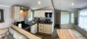 uma pequena cozinha com armários brancos e um sofá em Sunflower Lodge, Lido Leisure Park, Knaresborough em Knaresborough
