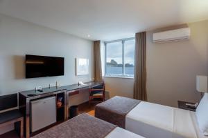 um quarto de hotel com uma cama e uma secretária com uma televisão em Orla Copacabana Hotel no Rio de Janeiro