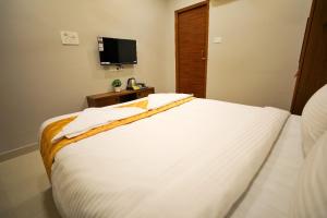 a bedroom with a white bed and a tv at Hotel Ceasta, Beside US Consulate Hyderabad, Gachibowli in Gundipet