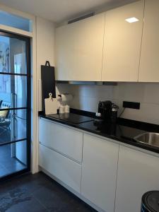 cocina con armarios blancos y encimera en Appartement 228 Bruinisse, en Bruinisse