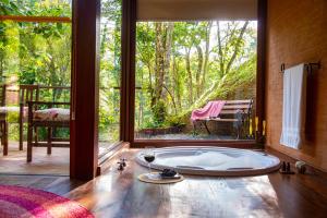 a bath tub in a room with a large window at Pousada Tijupá in Visconde De Maua