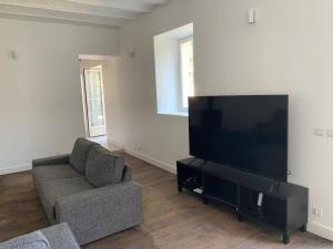 uma sala de estar com um sofá e uma televisão de ecrã plano em Gite tout confort - Vexin - Val d'Oise em Frémainville