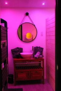 La salle de bains rose est pourvue d'un lavabo et d'un miroir. dans l'établissement Montbél' Appart Détente, à Montbéliard