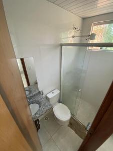 a small bathroom with a toilet and a glass shower at Chalés paradise - Família in Serra do Cipo