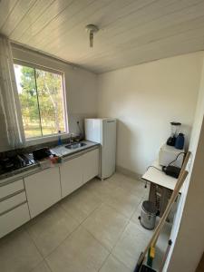 a kitchen with a white refrigerator and a window at Chalés paradise - Família in Serra do Cipo