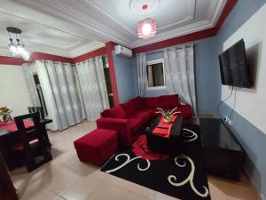 ein Wohnzimmer mit einem roten Sofa und einem Tisch in der Unterkunft LUXOR RESIDENCE YASSA DOUALA in Ngori