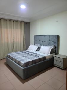 ein Schlafzimmer mit einem großen Bett mit einem großen Kopfteil in der Unterkunft LUXOR RESIDENCE YASSA DOUALA in Ngori