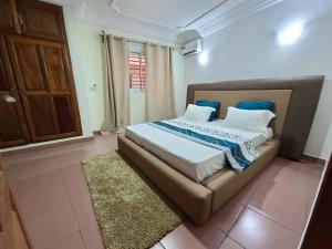 ein Schlafzimmer mit einem großen Bett mit blauen Kissen in der Unterkunft LUXOR RESIDENCE YASSA DOUALA in Ngori