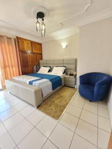 ein Schlafzimmer mit einem Bett und einem blauen Stuhl in der Unterkunft LUXOR RESIDENCE YASSA DOUALA in Ngori