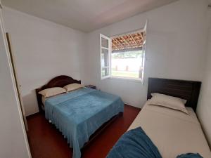 um quarto com 2 camas e uma janela em 3 QTS Churrasqueira Garagem perto do Forte e Ilha do Japonês em Cabo Frio