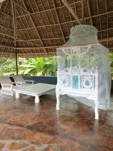 ein weißes Bett und eine Bank in einem Zimmer in der Unterkunft WHITE Nyumba in Malindi