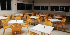 a dining room with white tables and yellow chairs at Hotel Dibeni Pereira in Pereira