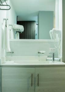 baño con lavabo y espejo grande en Hotel Dibeni Pereira en Pereira