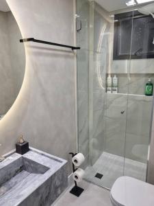 La salle de bains est pourvue d'une douche, d'un lavabo et de toilettes. dans l'établissement Lindo apto Frente MAR tudo novinho 2suítes+garagem, à Balneário Camboriú