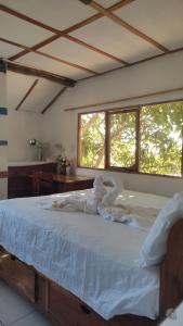 a bedroom with a bed with white sheets and windows at Flor's House in San Cristóbal
