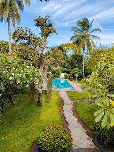 a garden with a swimming pool and palm trees at WHITE Nyumba in Malindi