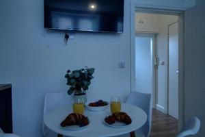 Excellent One Bedroom Apartment Dundee في دندي: طاولة بيضاء مع طبقين من الطعام وعصير برتقال