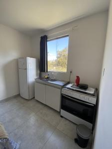 a kitchen with a stove and a refrigerator and a window at Chalés Paradise - Casal in Serra do Cipo