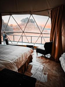 a room with a bed and a chair and a window at Wadi Rum Rose camp in Wadi Rum