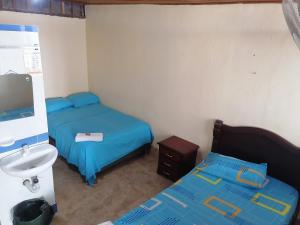 Habitación pequeña con 2 camas y lavamanos en Posada Turística Noches De Saturno, en Villavieja