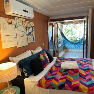 1 dormitorio con 1 cama con una manta colorida en Casa de CINEMA 3 suites, 50m da Praia da Ferradura, en Búzios