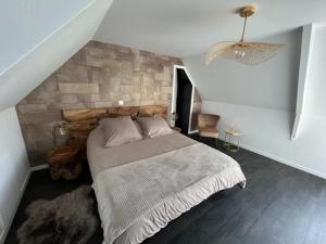 ein Schlafzimmer mit einem Bett mit einer Steinmauer in der Unterkunft Clos de la Lainerie in Gouville-sur-Mer