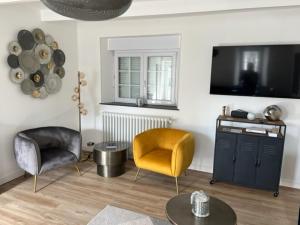 ein Wohnzimmer mit 2 Stühlen und einem TV in der Unterkunft Clos de la Lainerie in Gouville-sur-Mer