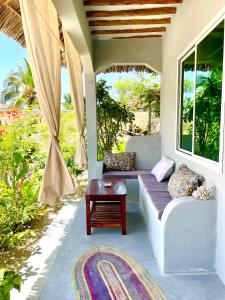 a porch with a couch and a coffee table at Butterfly Apartment Zanzibar in Bwejuu