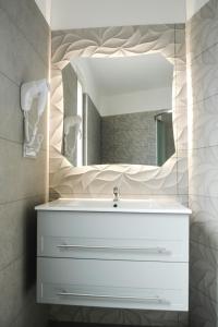 La salle de bains est pourvue d'un lavabo blanc et d'un miroir. dans l'établissement Home Pacifico, à Vibo Valentia