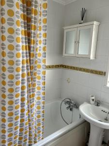 y baño con bañera, lavamanos y cortina de ducha. en 2 Bedroom Chalet Close to Beach, en Hemsby 5 fotos más