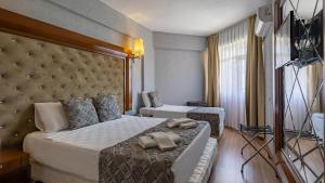 ein Hotelzimmer mit einem großen Bett und einem Stuhl in der Unterkunft Lara Olympos Hotel in Antalya