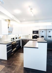 a large kitchen with white cabinets and appliances at Apartment next to Ounasvaara and city centre in Rovaniemi