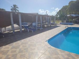 a swimming pool in a yard with chairs next to at Casitas na Praia in Barra de Santo Antônio