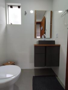 y baño con lavabo, aseo y espejo. en CASA DE PRAIA, en Garopaba
