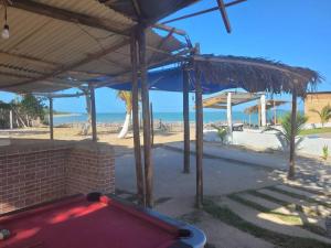a red pool table under a pavilion next to the beach at Casitas na Praia in Barra de Santo Antônio