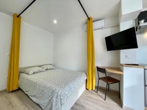 a bedroom with a bed with yellow curtains and a desk at cosy douillet la grande motte in La Grande-Motte