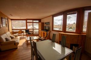 a living room with a table and chairs and windows at Tignes Le Lac - Appartement au pied des pistes (6 personnes) in Tignes