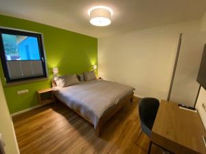 a bedroom with a bed and a green wall at Barrierefreies Ferienapartment A2 Villa Wilisch 55qm in Amtsberg
