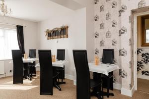 The Bell Lodge في سانداون: غرفة طعام مع طاولات بيضاء وكراسي سوداء