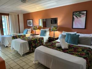 a hotel room with two beds and two chairs at Búzios Prime: Vista Mar, 50m da Praia da Ferradura, 8 suites in Búzios