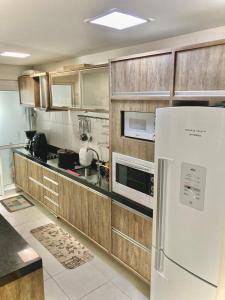 a kitchen with a white refrigerator and wooden cabinets at Condomínio Encantador - Beto Carrero - 3 quartos in Penha
