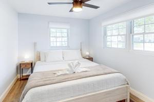 a white bedroom with a large bed with a fan at Seminole's Secret in Redington Shores