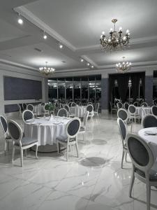 a banquet hall with white tables and chairs and a chandelier at Grand Hotel Kapan, Armenia in Kapan