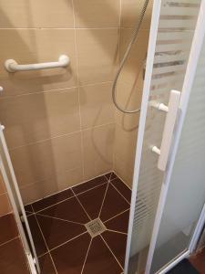 a shower with a glass door and a tile floor at Station House - Maison entre Disneyland et Paris in Roissy-en-Brie