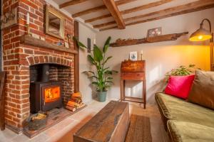 a living room with a brick fireplace and a couch at Most romantic cottage in Suffolk - Number Four in Framlingham