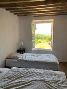 Duas camas num quarto com uma janela em Gite tout confort - Vexin - Val d'Oise em Frémainville