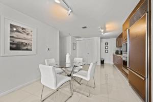 une salle à manger avec une table en verre et des chaises blanches dans l'établissement Luxury 1 BR Condo W Icon Brickell-Waterviews, à Miami