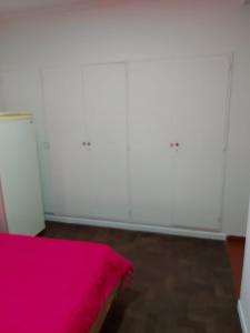 una camera con letto rosa e pareti bianche di Depto casique 2pax a Necochea