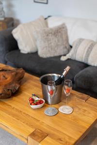 a table with two glasses of wine and a bowl of strawberries at The Amazing Attic Apartment in Skipton